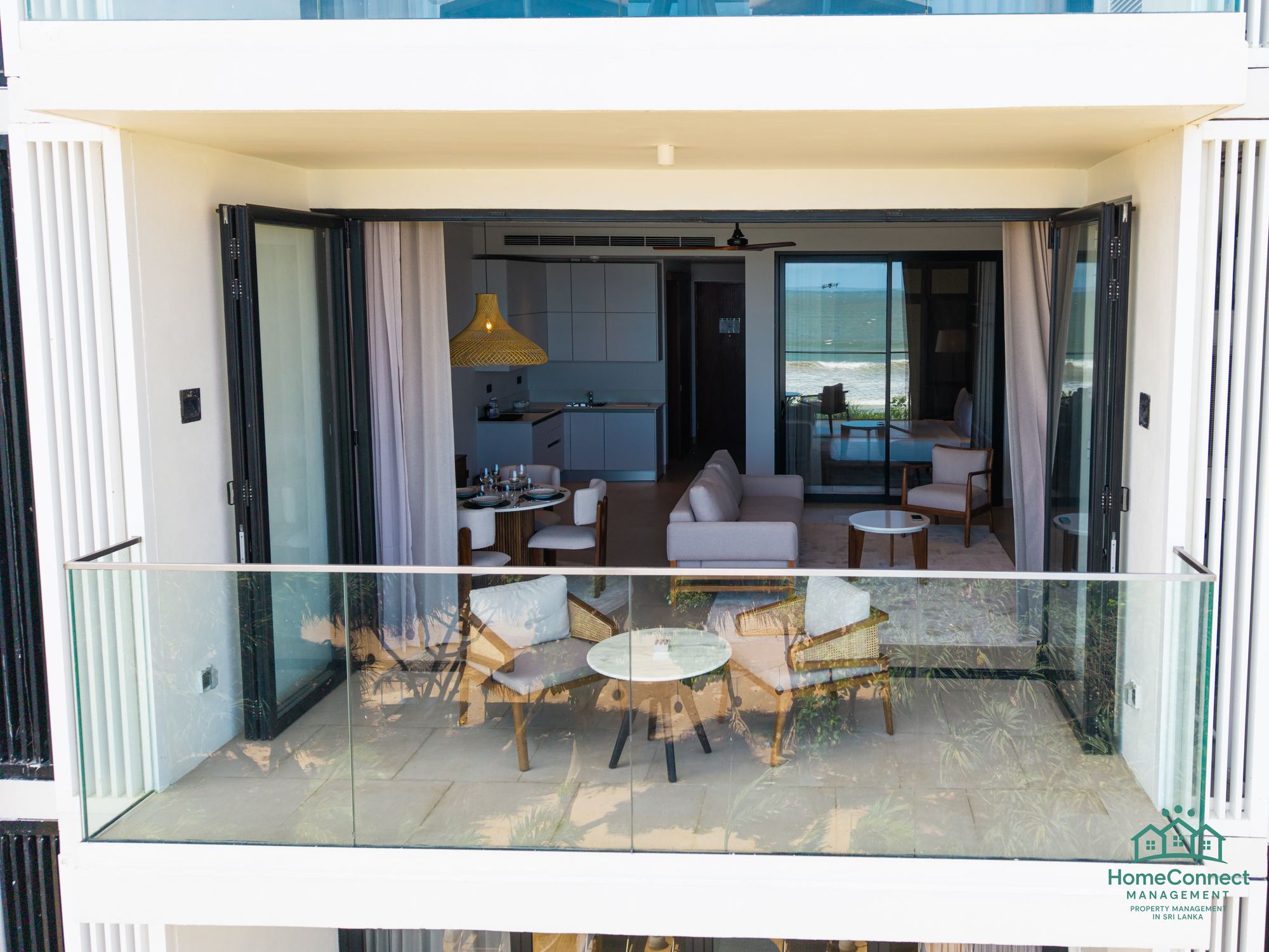Aerial view of Weligama Bay: the pool deck, palms and the surf beach beside a HomeConnect apartment